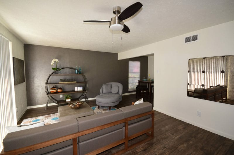 Living room with gray sectional sofa, dark accent wall, and decorative shelves.