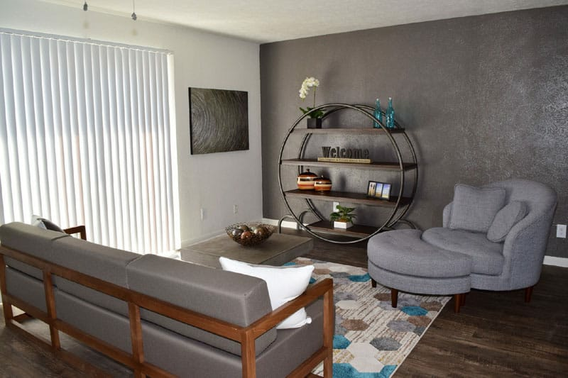 Living room with gray sofa, chair, and circular bookshelf; dark accent wall.