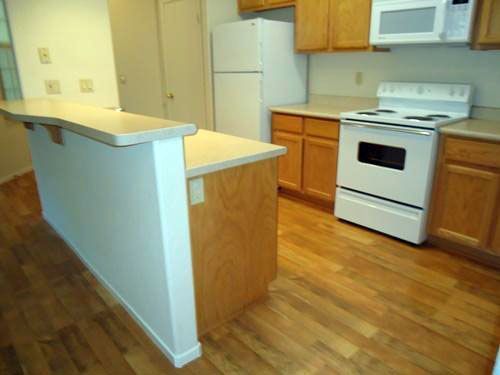 Kitchen with a breakfast bar, white appliances, and light wood cabinetry.