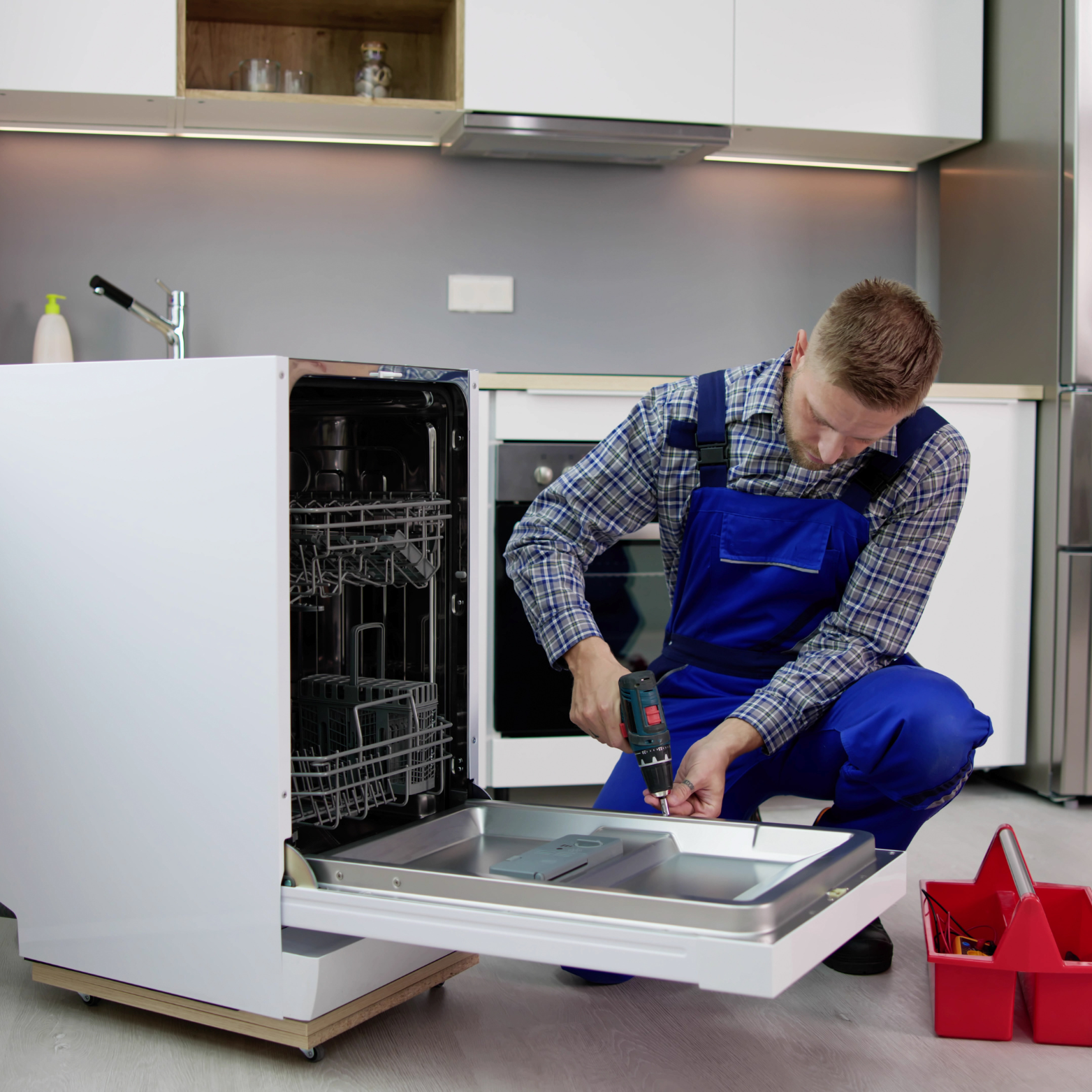 A man is working on a dishwasher in a kitchen