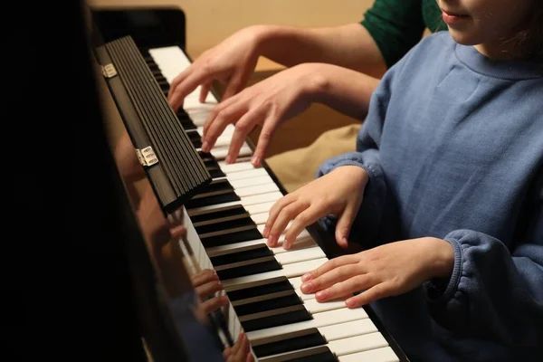 A man and a child are playing a piano together