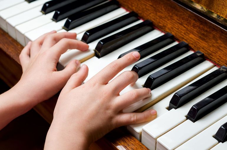 A person is playing a piano with their hands on the keys.