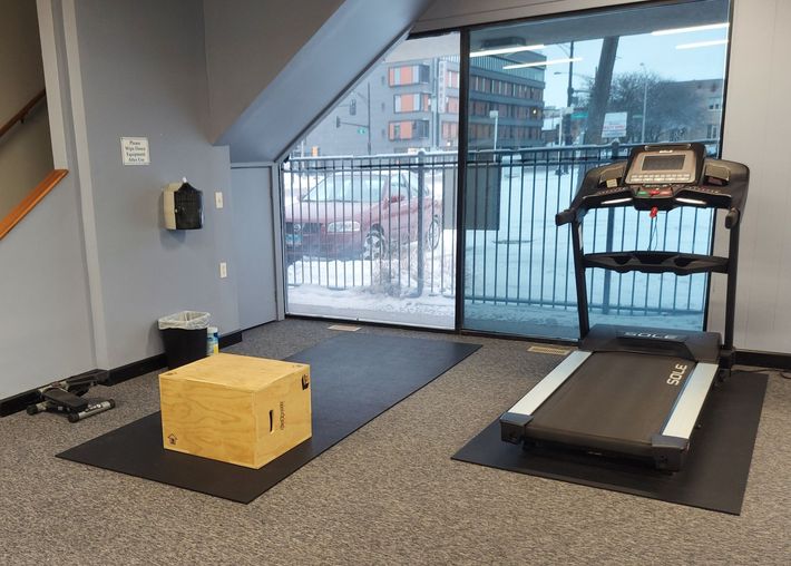 A gym with a treadmill and a box on the floor.