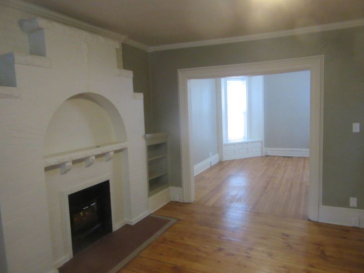 An empty living room with a fireplace and hardwood floors