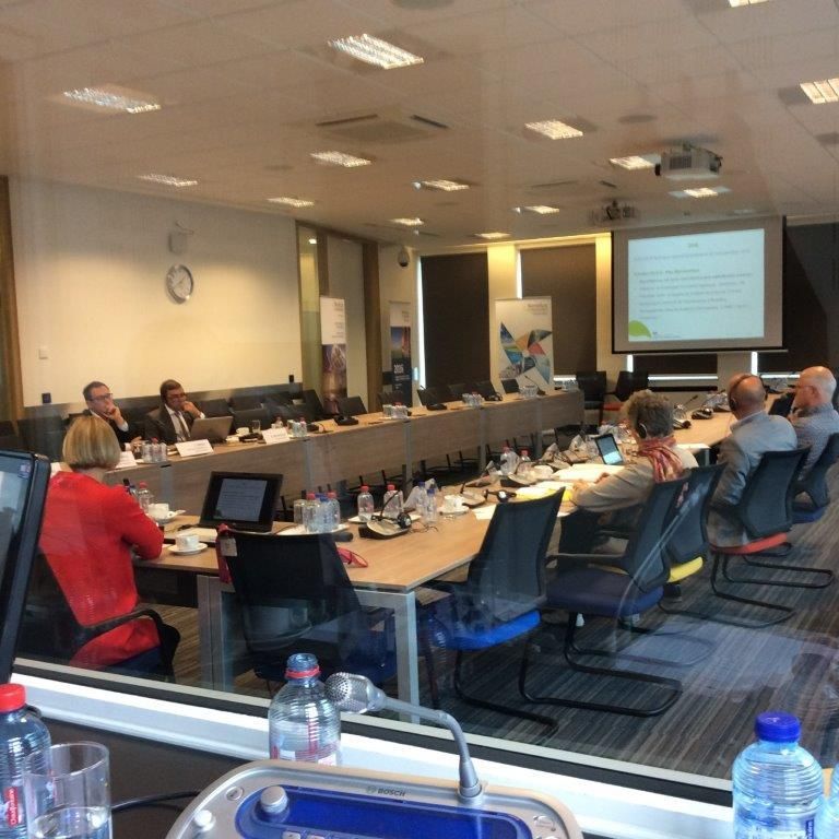 Eine Gruppe von Menschen sitzt an langen Tischen in einem Konferenzraum