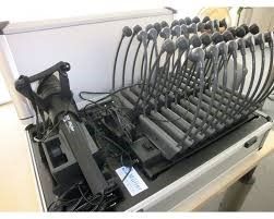 Open metalen behuizing met veel microfoons, hoofdtelefoons en apparatuur.