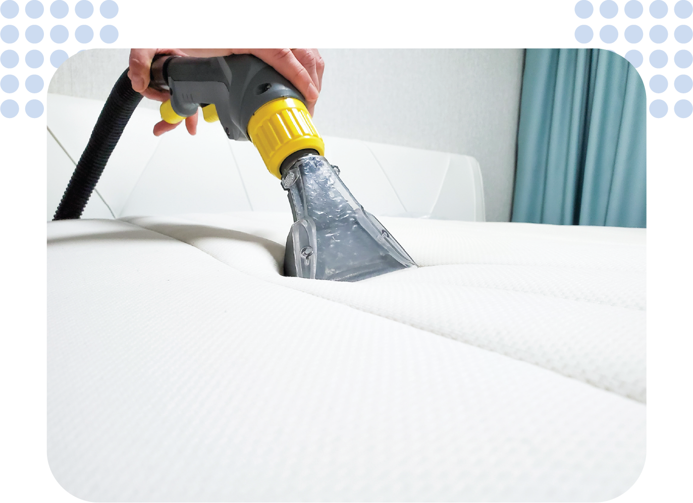 A person is cleaning a white couch with a vacuum cleaner.