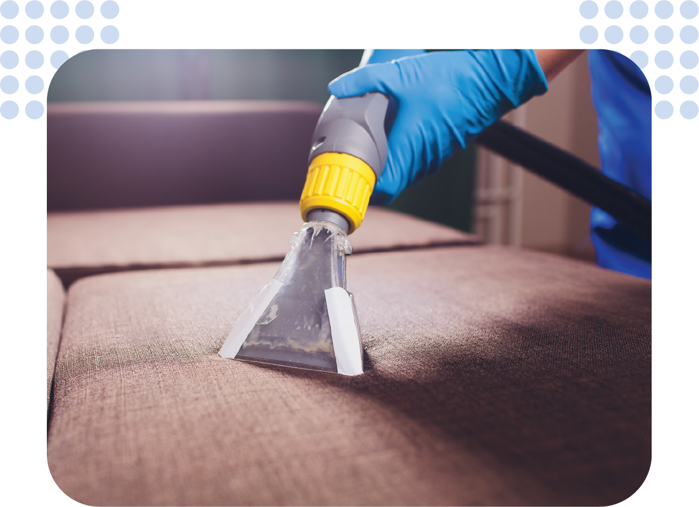 A person is cleaning a couch with a vacuum cleaner.