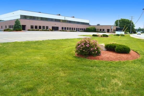 Building with green lawn, small bushes and flowers, sunny day.