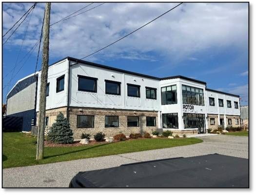 Modern two-story building with a white upper level and a brick lower level. Green lawn and blue sky.