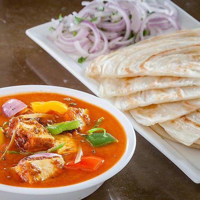 A bowl of soup next to a plate of food on a table.