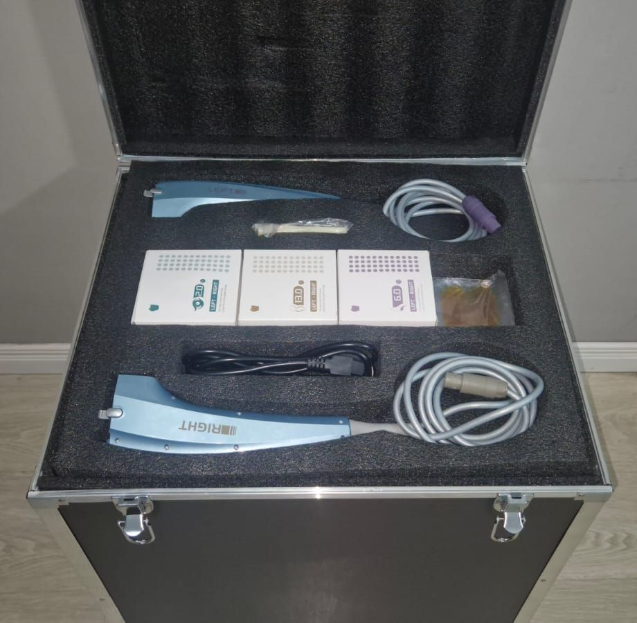 Estuche abierto que contiene equipo médico, posiblemente para odontología, con piezas de mano y documentación.