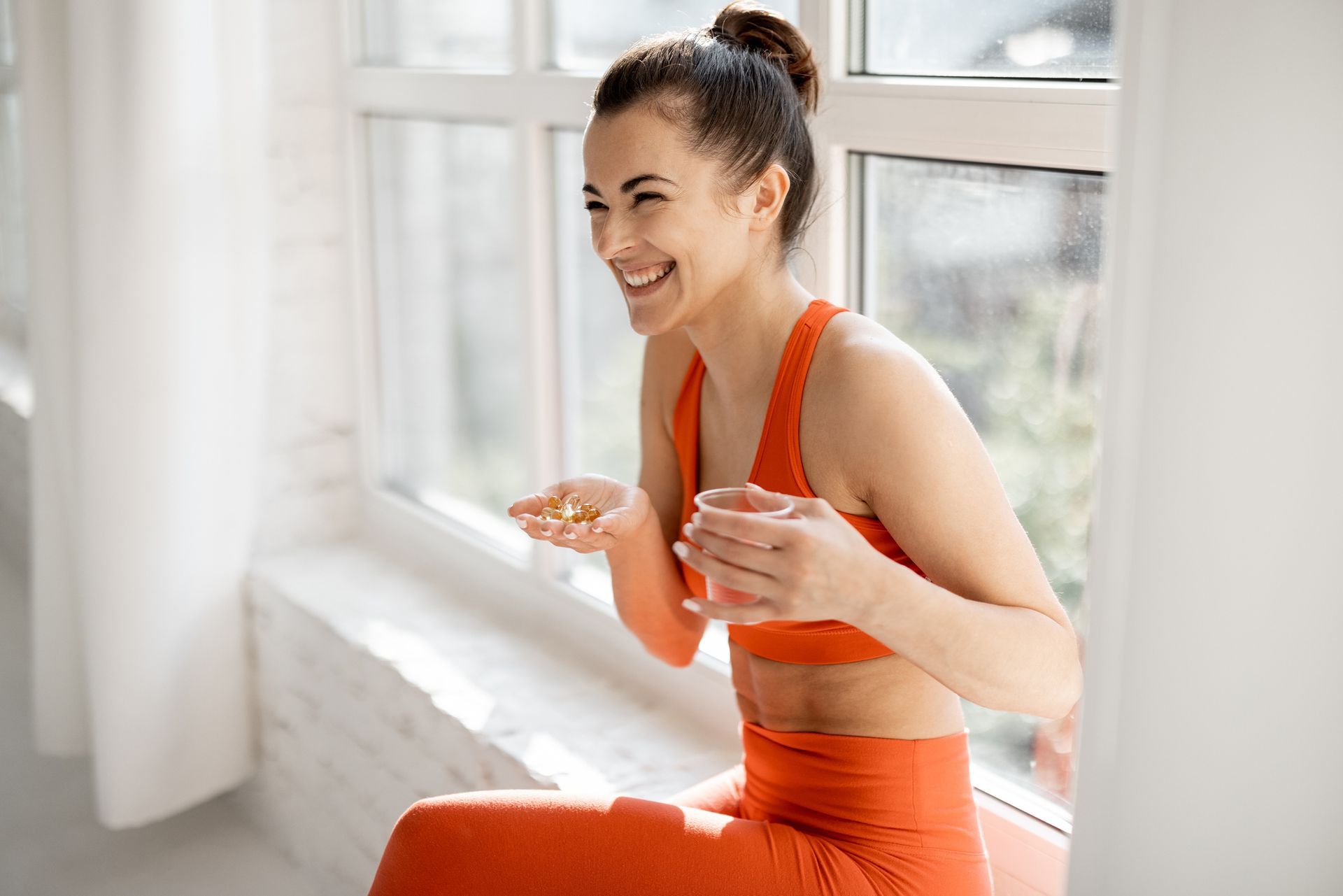 A woman in an orange sports bra sits on a window sill, promoting weight loss products in Bullhead Ci