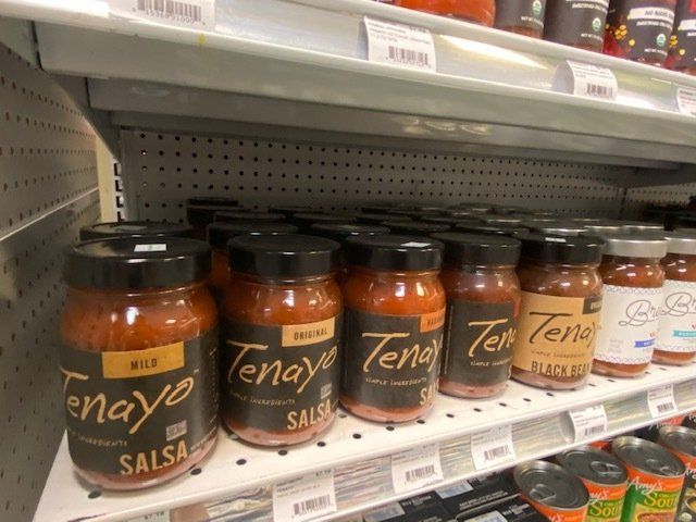 Several jars of tenay salsa are lined up on a shelf