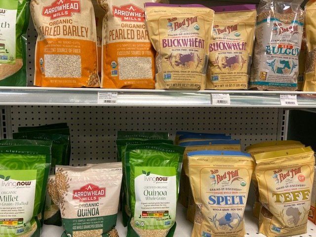 A shelf filled with bags of grains including spelt and buckwheat