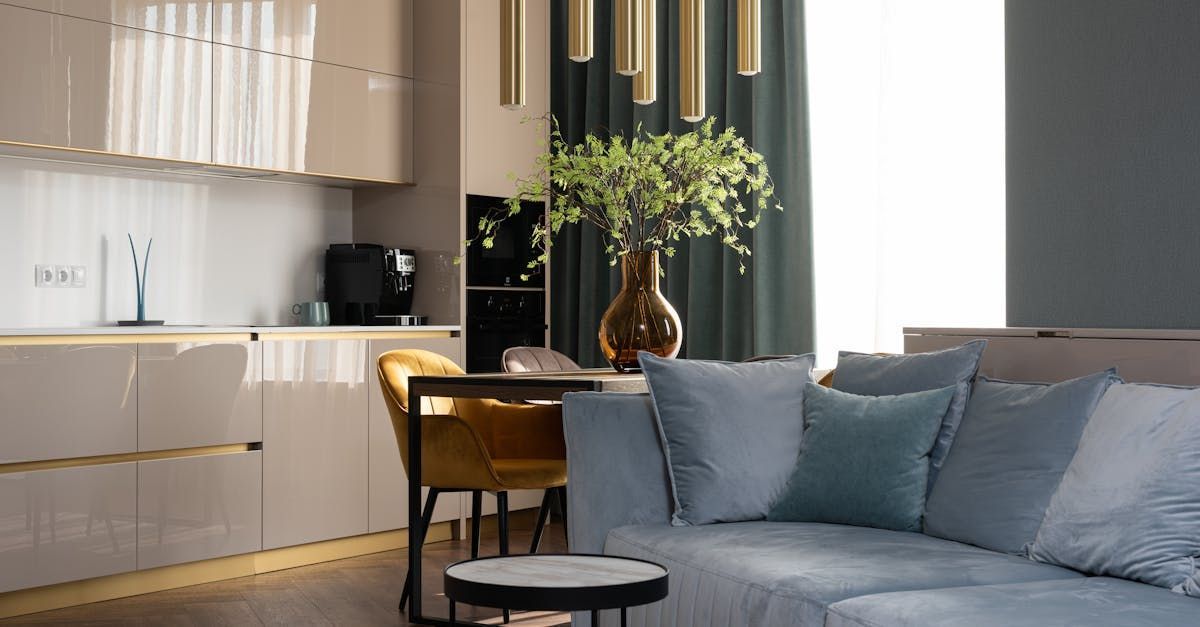 A living room with a couch , table , chairs and a vase of flowers.