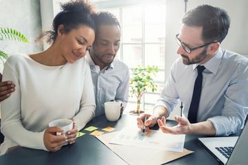 A man is sitting at a table talking to a couple.
