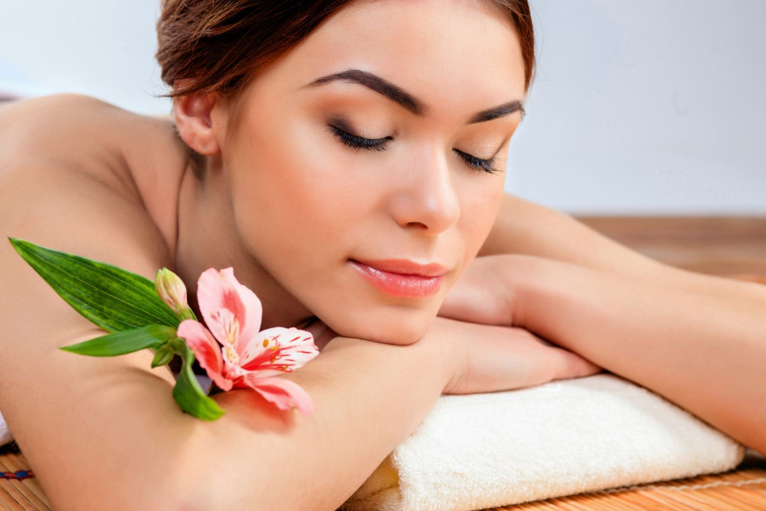 A woman is laying on a towel with a flower on her arm.