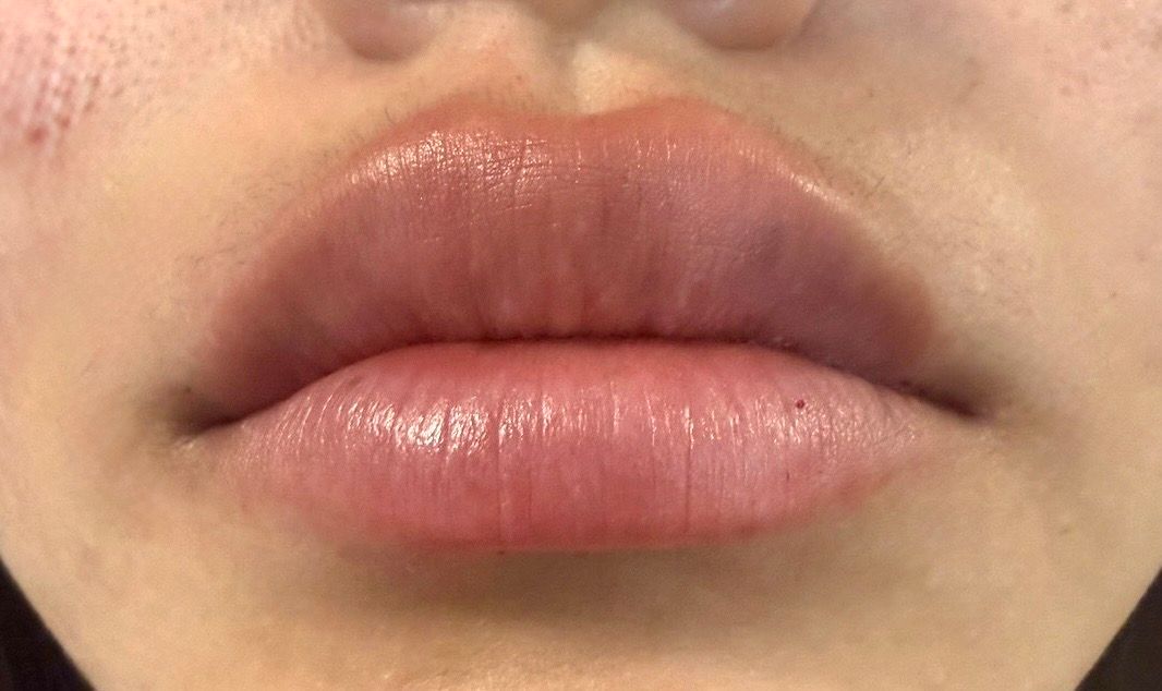 Close-up of glossy pink lips and lower face against a blurred background