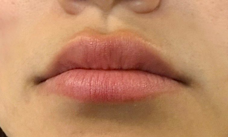 Close-up of lips with soft pink lipstick on a neutral face.