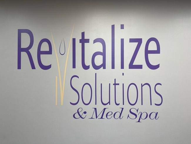 The logo for revitalize solutions and med spa is on a wall.