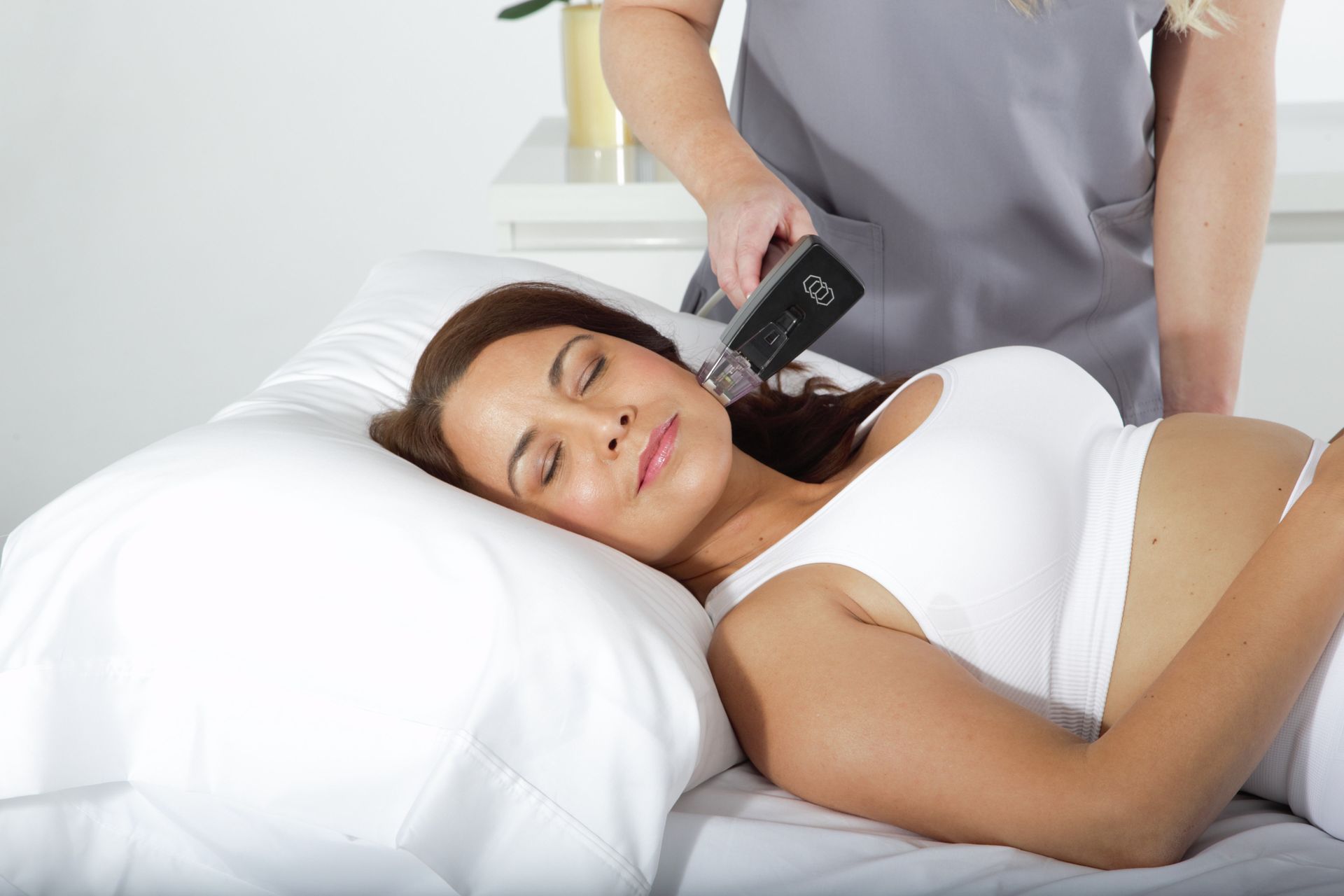 Woman receiving a handheld neck treatment on a spa bed