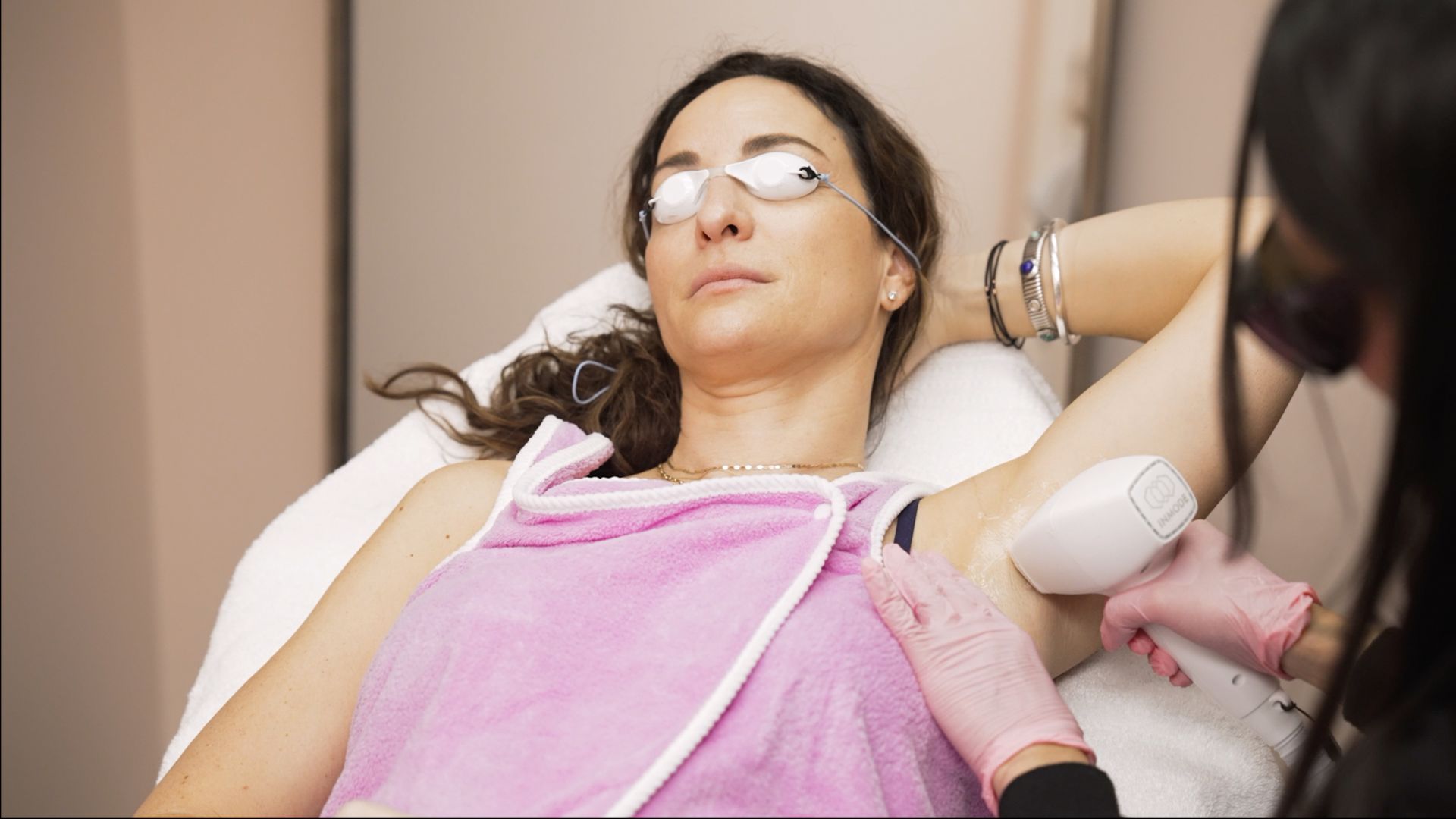 A woman is getting a laser hair removal treatment on her underarm.