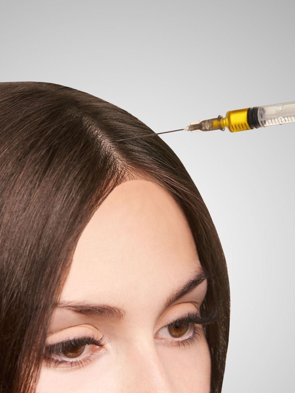 A woman is getting a botox injection in her forehead