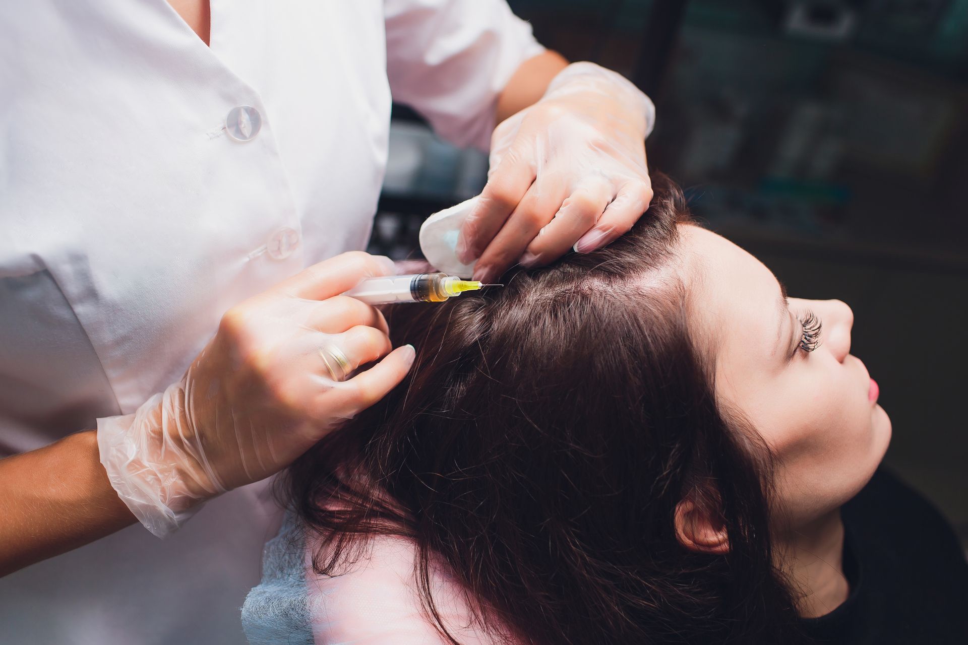 A woman is getting an injection in her hair.