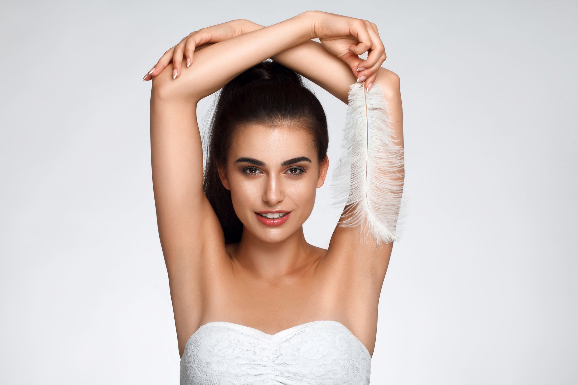 A woman in a white dress is holding a white feather in her hand.