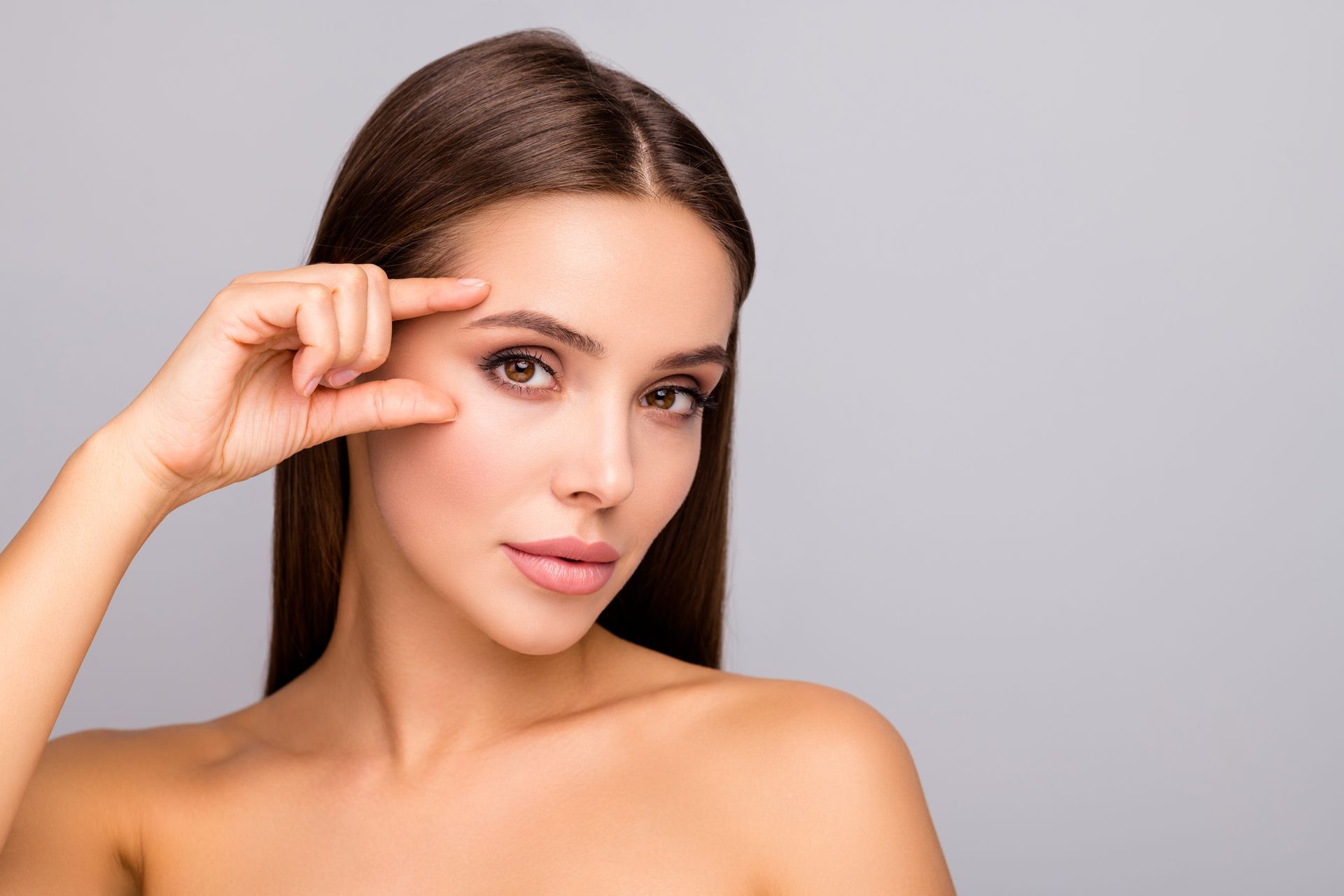 A woman is touching her eye with her finger.