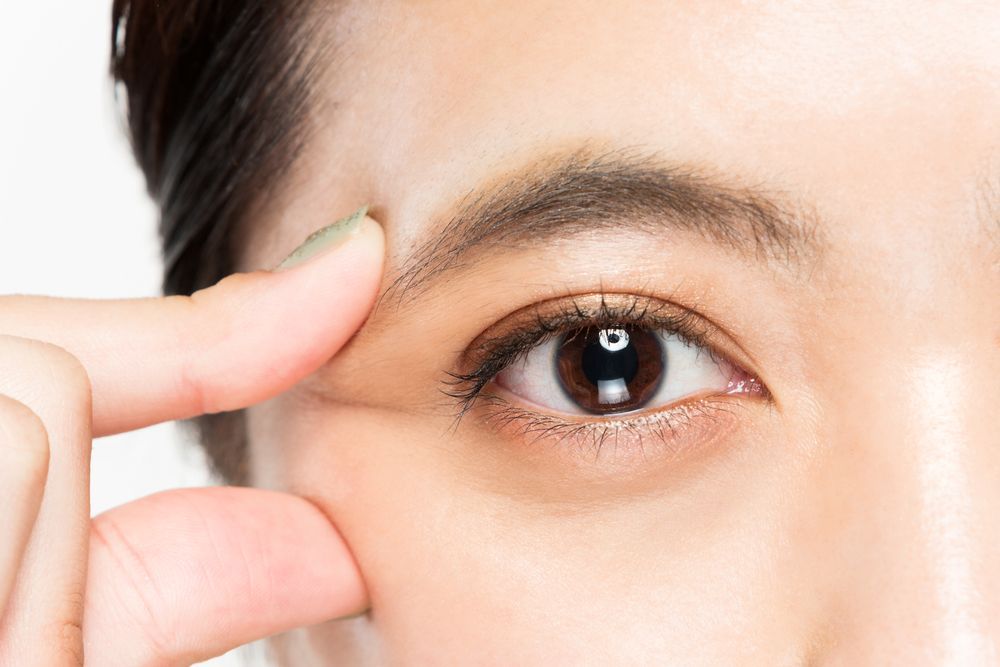 A close up of a woman 's eye with her finger on it.