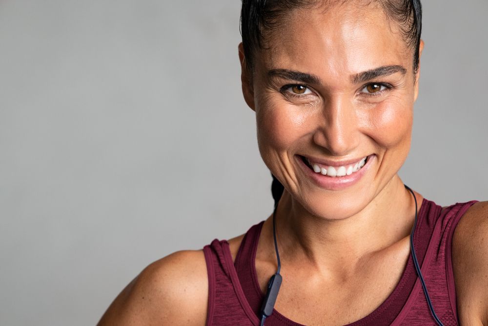 A close up of a woman wearing headphones and smiling.