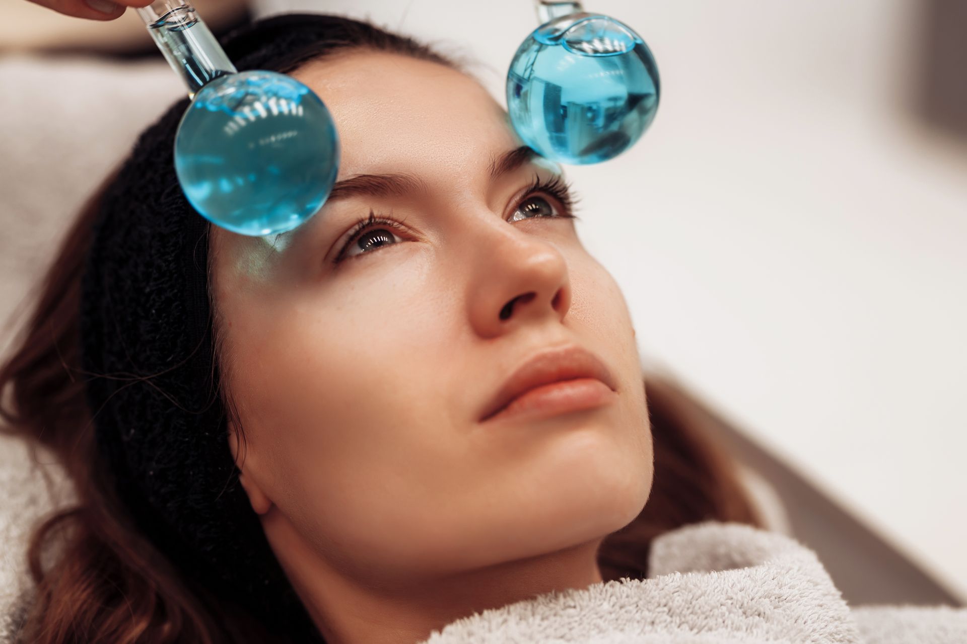 A woman is getting a facial treatment with ice balls on her forehead.