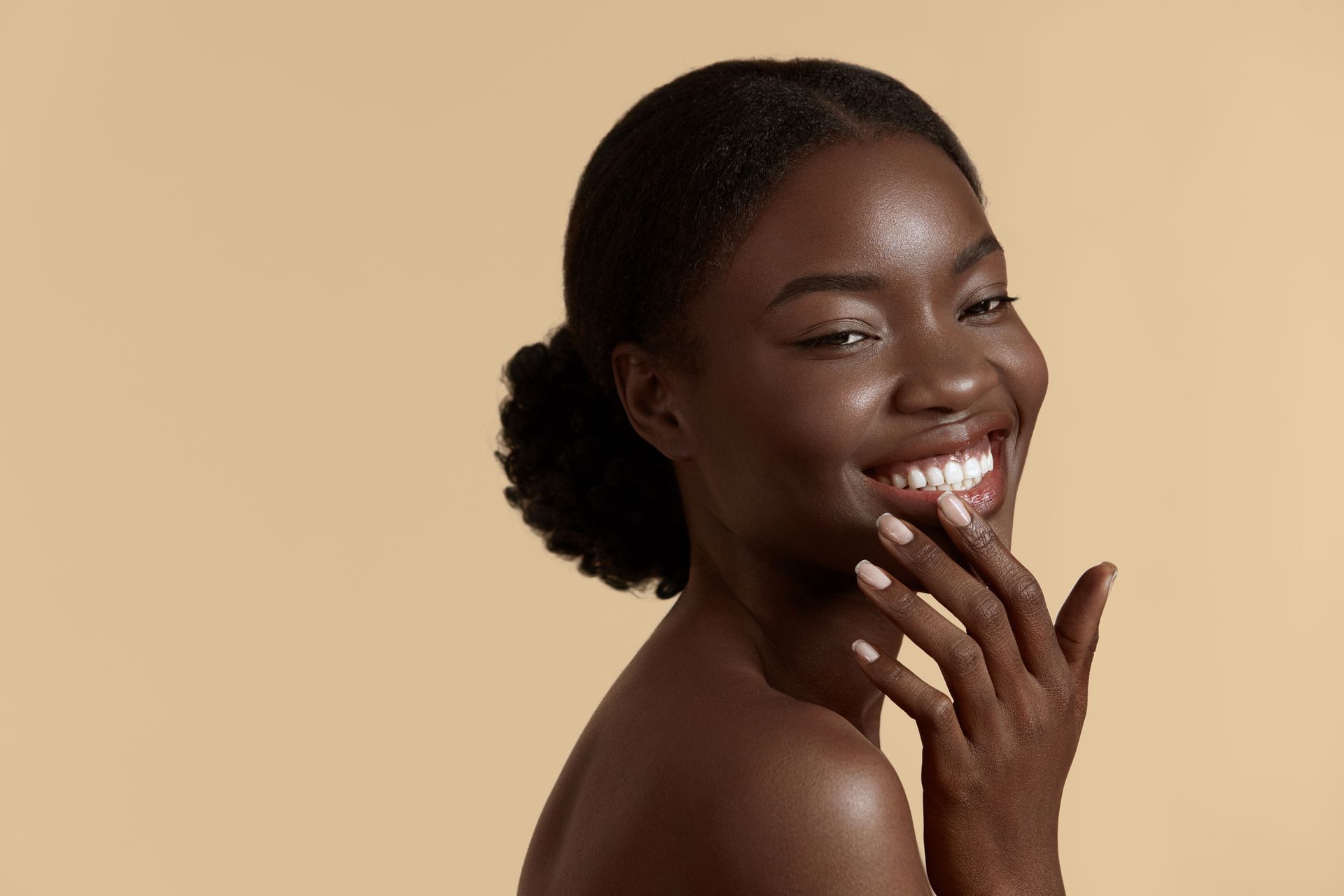 A woman is smiling and touching her face with her hands.