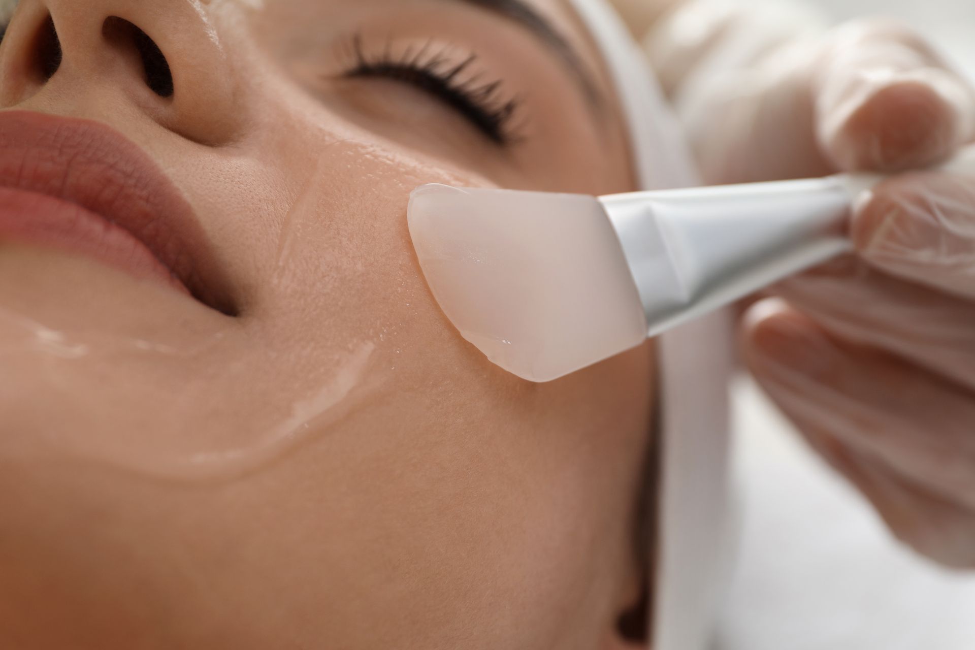 A woman is getting a facial treatment with a brush.