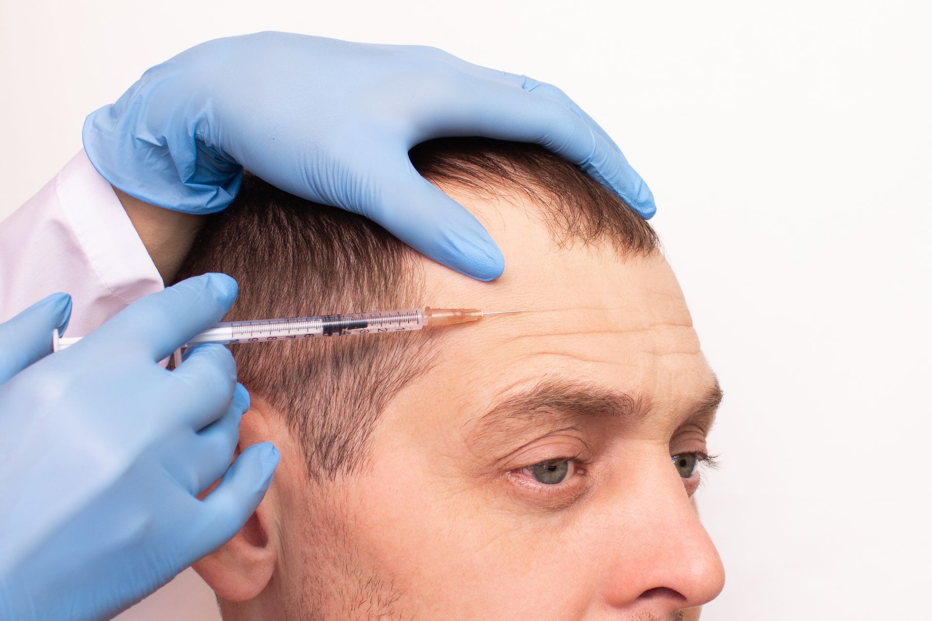 A person receiving an injection in their forehead. Gloved hands holding a syringe.