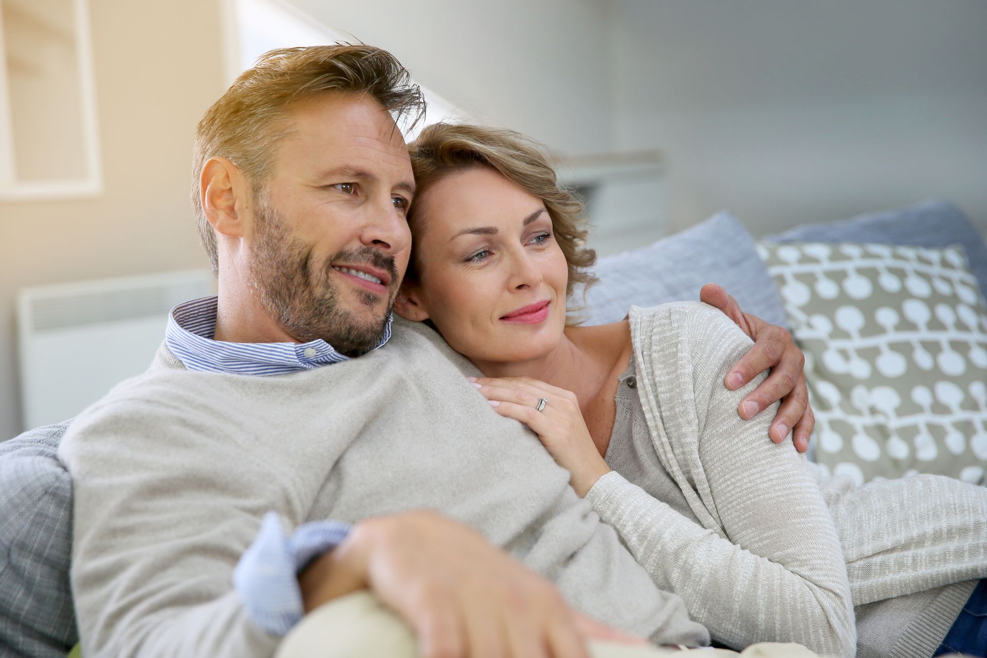 A man and a woman are sitting on a couch hugging each other.