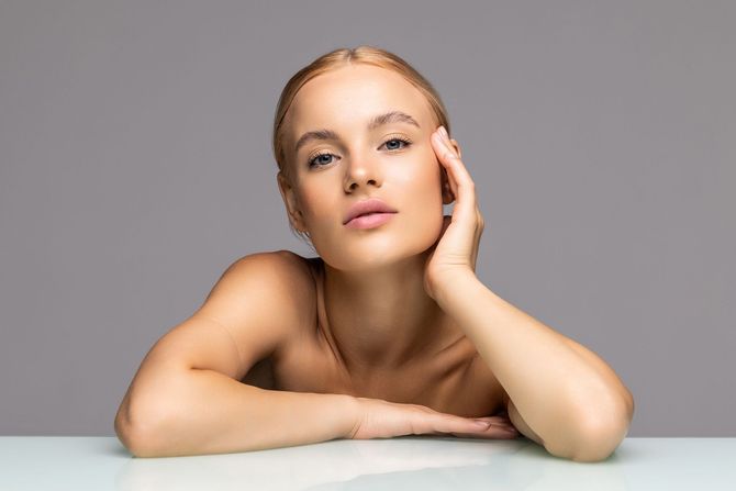 A woman is sitting at a table with her hand on her face.