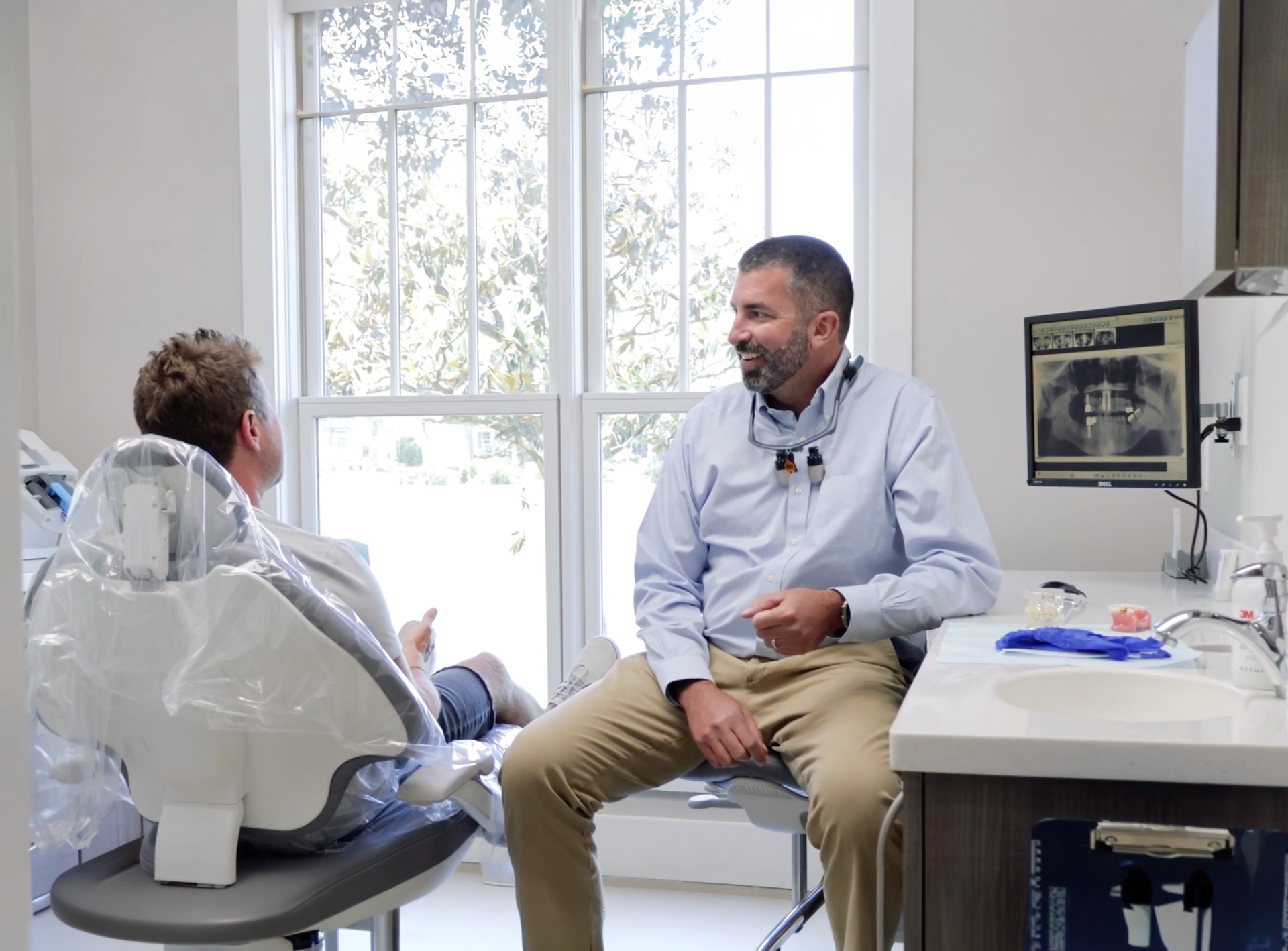 Patient reclining in a dental chair during a dental treatment, with equipment and tools nearby