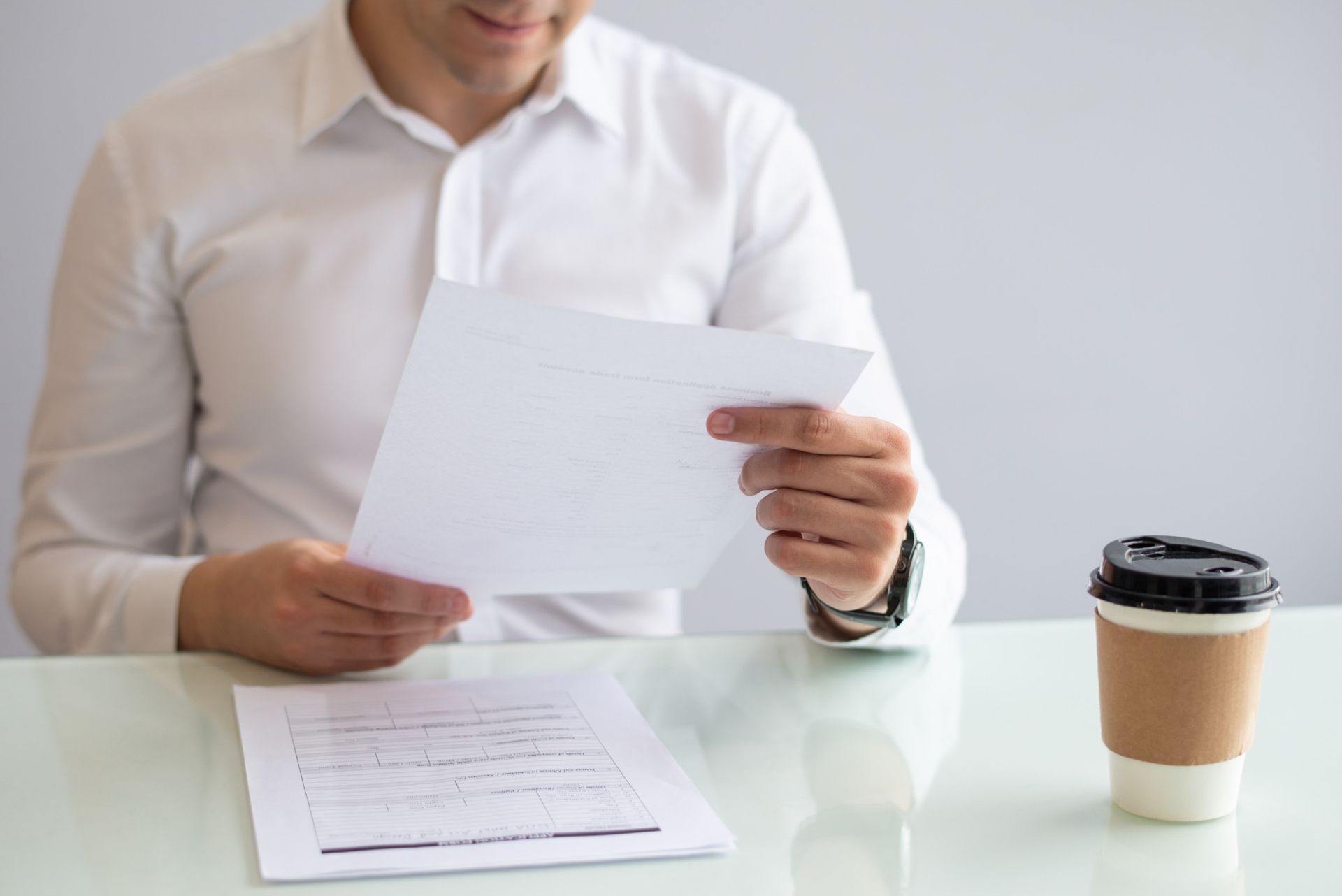 A man is sitting at a desk holding a piece of paper.