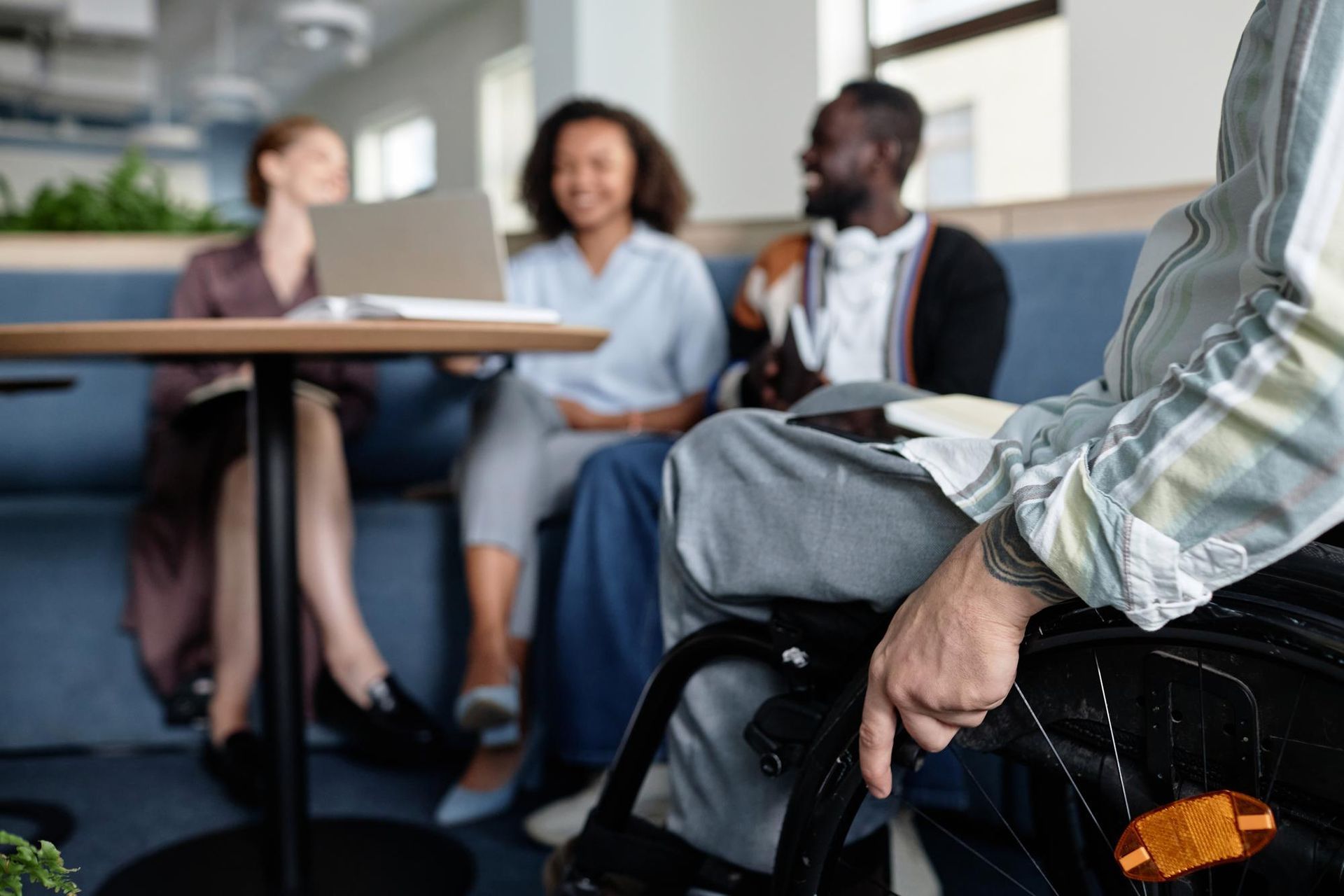 A man in a wheelchair is sitting at a table with other people.