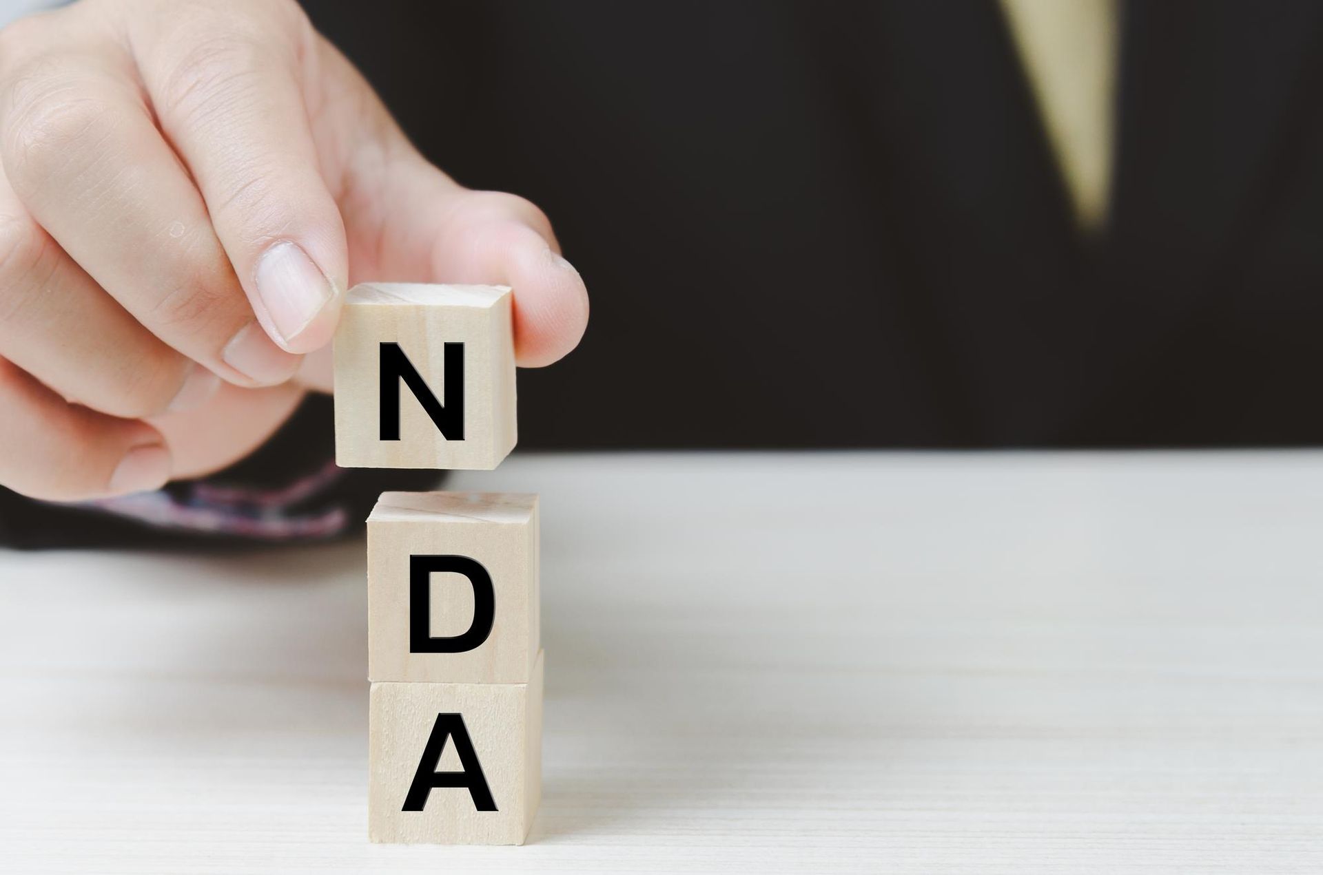 Hand arranging NDA blocks, symbolising non-disclosure agreements in the workplace