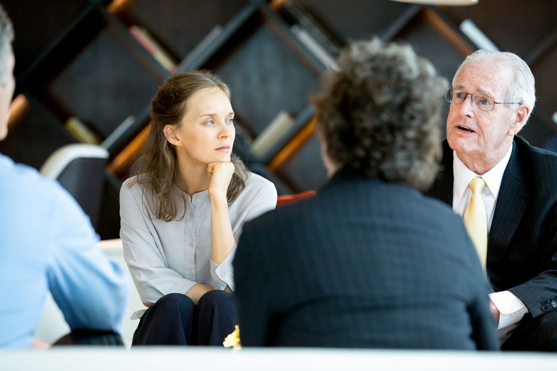 A group of people are sitting around a table having a conversation.