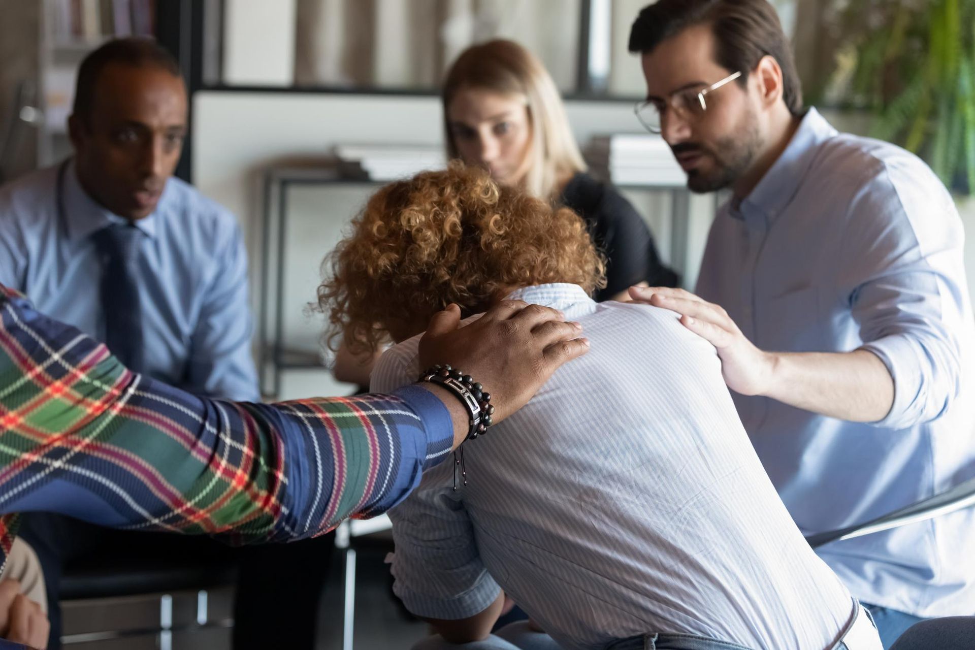 A group of people are sitting around a table with their hands on each other.