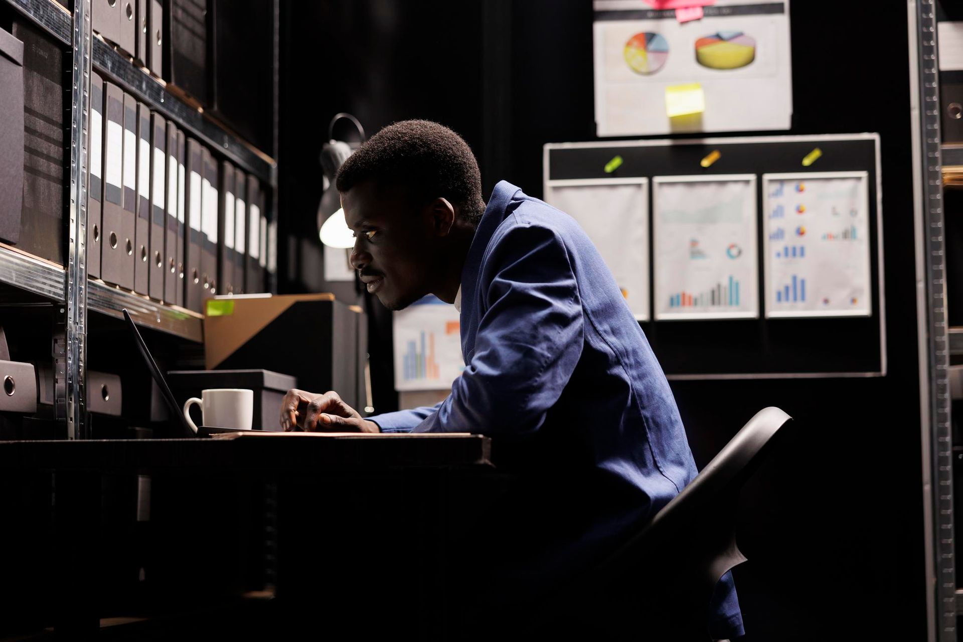 a man is sitting at a desk in a dark room using a laptop computer. GDPR