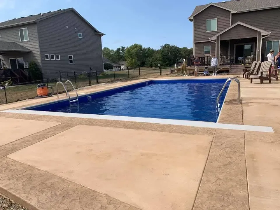 There is a large swimming pool in the backyard of a house.