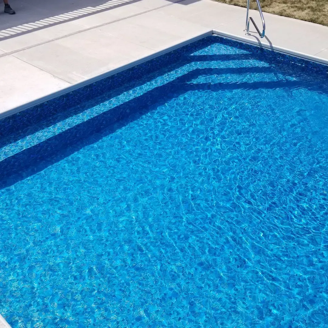 A large swimming pool filled with blue water and a ladder.