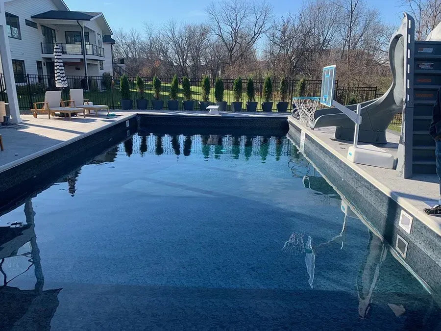 A large swimming pool with a house in the background