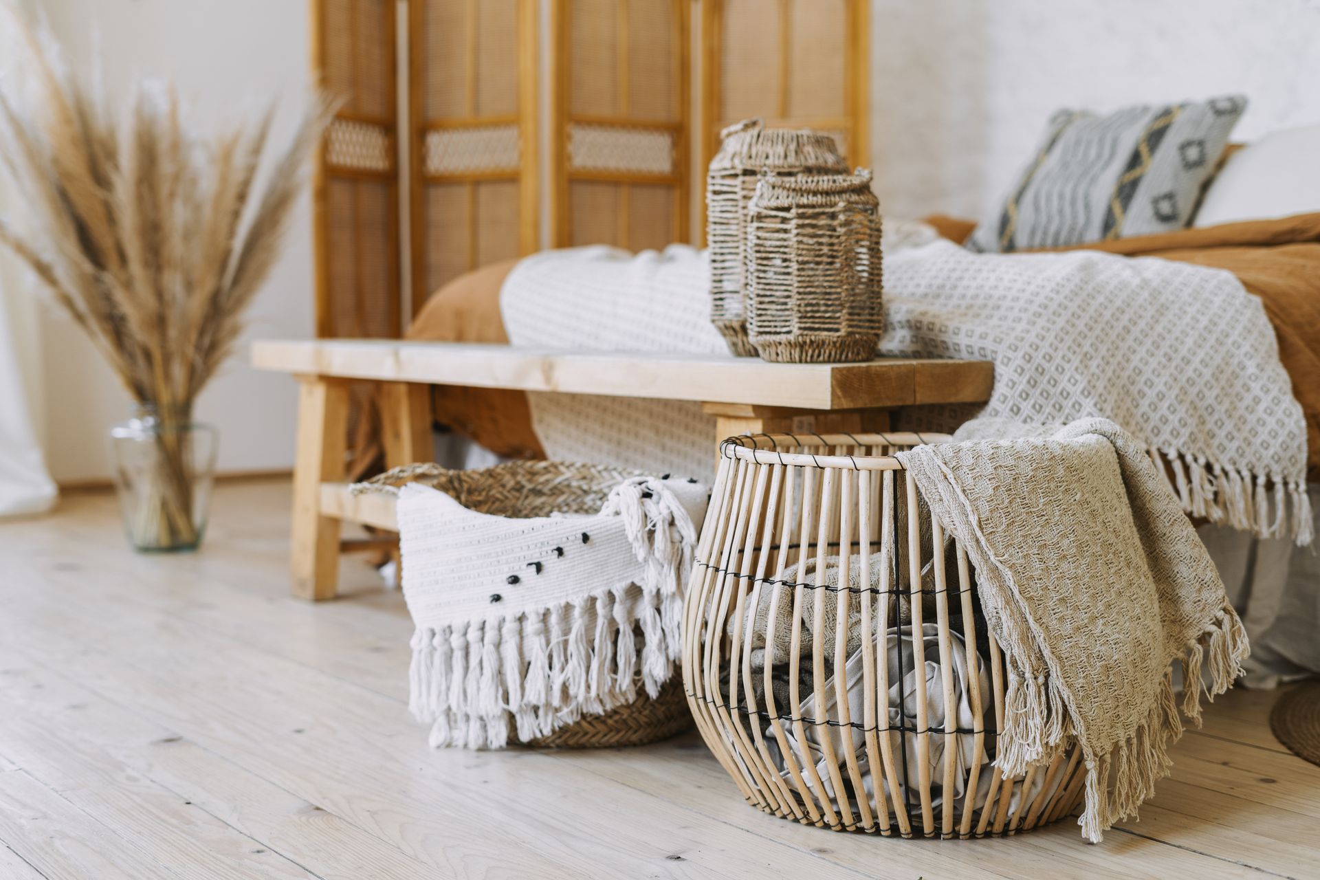A bedroom with a bed , wicker baskets , and a wooden bench.